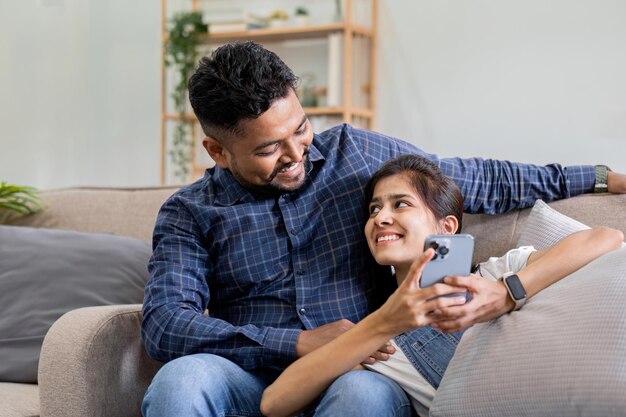 Een stel dat op de bank zit en naar hun mobiele telefoons kijkt, glimlacht en lacht samen tijdens