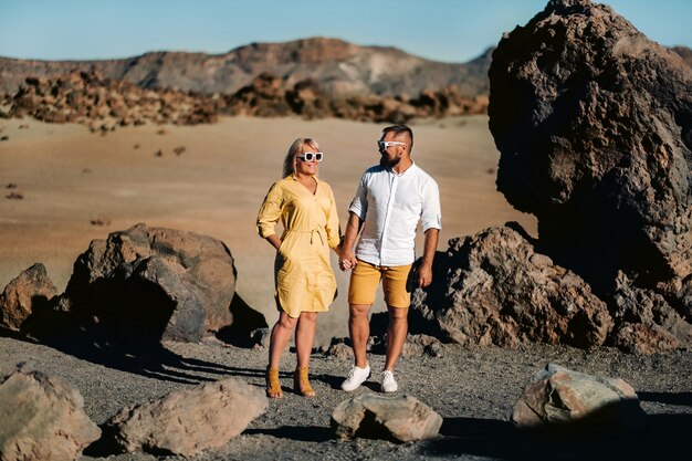 Een stel, een vrouw en een man in de woestijnkrater van de vulkaan teide en genieten van het uitzicht op de zonsondergang. reis naar de bergen, vrijheid en het concept van een actieve levensstijl. canarische eilanden, spanje.