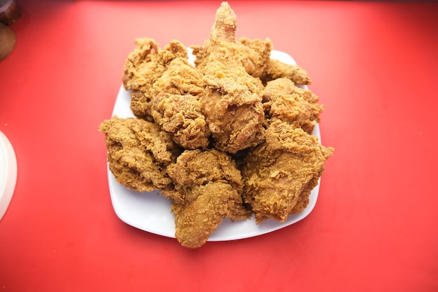 Een stel gebakken kip wordt op een tafel met rode achtergrond geplaatst