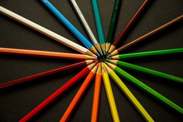 Een stel kleurrijke potloden raken elkaars hoofden aan