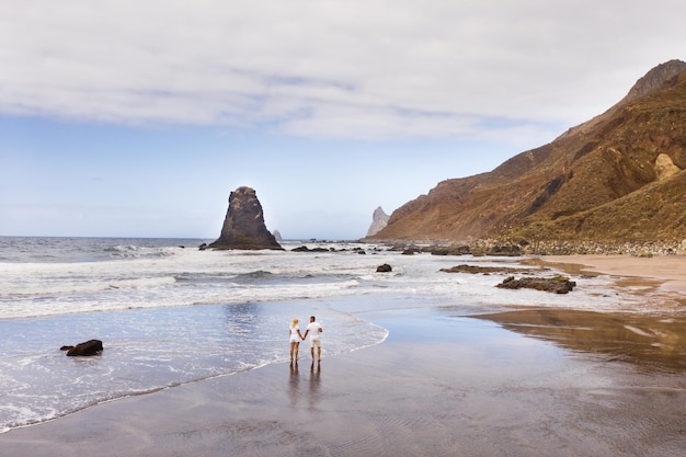 Een stel loopt op het zandstrand van Benijo op het eiland TenerifeDe Canarische Eilanden Spanje