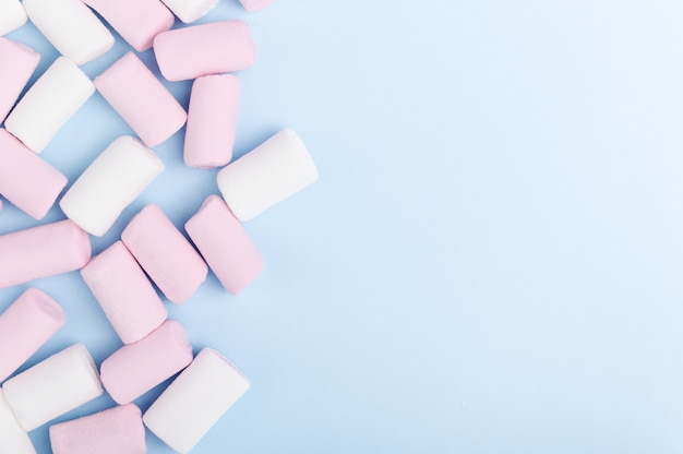 Een stel witte en roze marshmallows op een pastelkleurige lichte achtergrond.