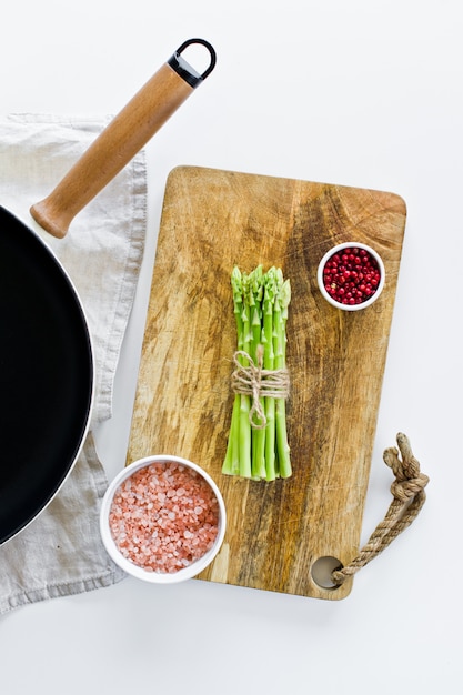 Een stelletje mini-asperges op een houten snijplank.