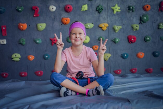 Een sterke baby klimmer die poseert voor een fotograaf bij een kunstmatige muur