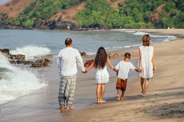 Een sterke familie loopt van achteren langs het strand