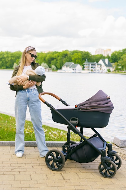 Een stijlvol geklede jonge moeder kalmeert een kind in haar armen tijdens een wandeling in het park