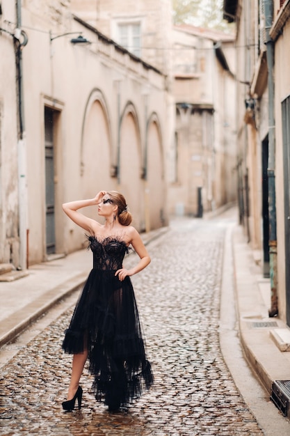 Een stijlvolle bruid in een zwarte trouwjurk poseert in de oude Franse stad Avignon. Model in een mooie zwarte jurk. Fotoshoot in de Provence.