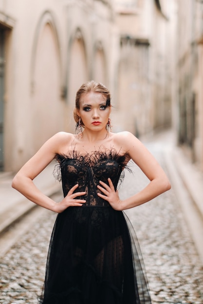 Een stijlvolle bruid in een zwarte trouwjurk poseert in de oude Franse stad Avignon. Model in een mooie zwarte jurk. Fotoshoot in de Provence.