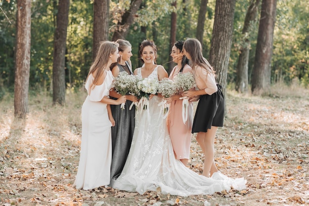 Een stijlvolle bruidegom in een wit hemd en een schattige brunette bruid in een witte jurk cirkelen op een asfaltweg tegen de achtergrond van een bos en bergen zwart-wit foto