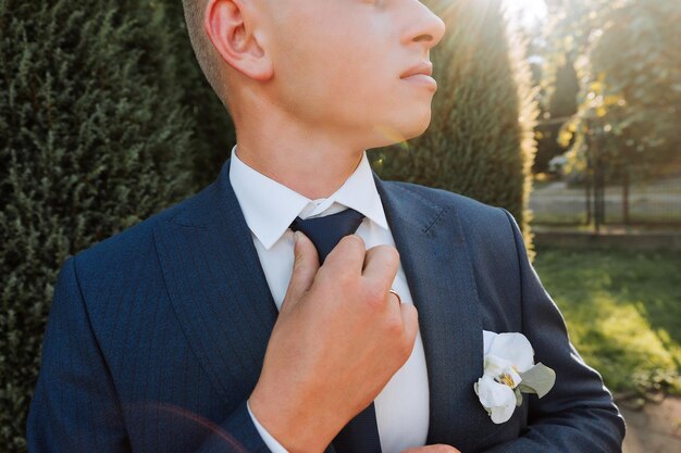 Een stijlvolle bruidegom in een zwart pak en een schattige bruid in een witte jurk met een lange sluier knuffelen in een park Wedding portret van glimlachende en gelukkige pasgetrouwden