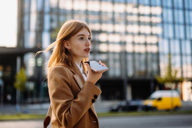 Een stijlvolle en zelfverzekerde professionele vrouw in een stedelijke omgeving met een trenchcoat en blazer