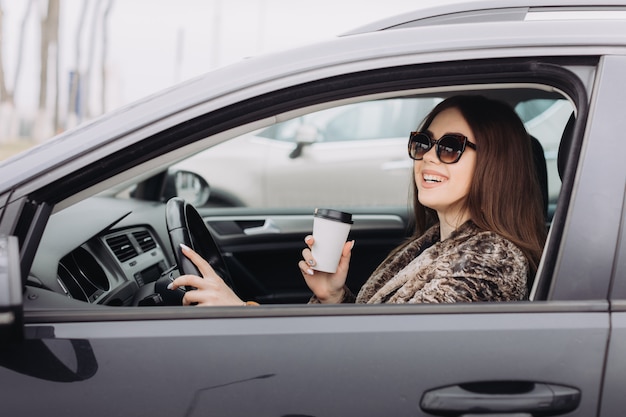 Een stijlvolle jonge vrouw zoekt een nieuwe auto in een autowinkel