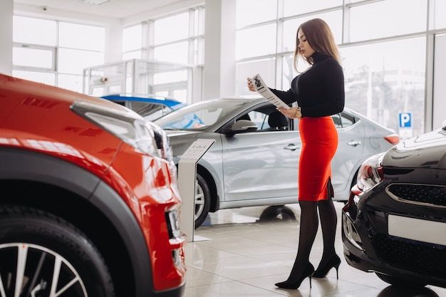 Een stijlvolle jonge vrouw zoekt een nieuwe auto in een autowinkel