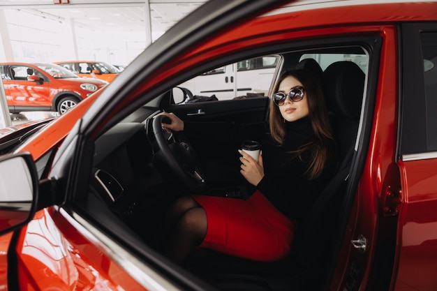 Een stijlvolle jonge vrouw zoekt een nieuwe auto in een autowinkel