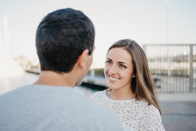 Een stijlvolle jongeman houdt handen vast met zijn brunette vriendin in de haven