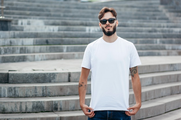 Foto een stijlvolle jongeman met een baard in een wit t-shirt en een bril