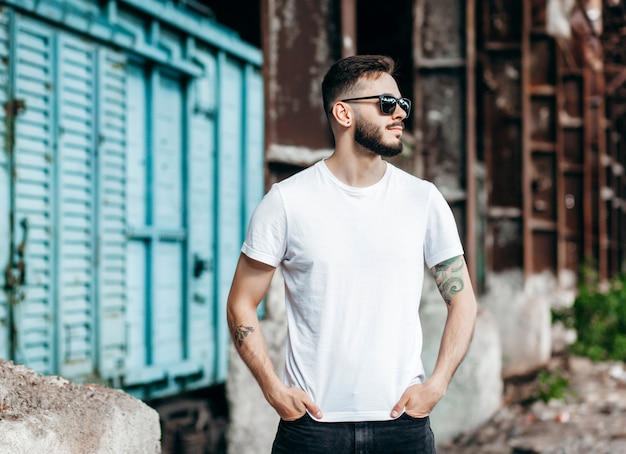 Een stijlvolle jongeman met een baard in een wit T-shirt en glasplaten