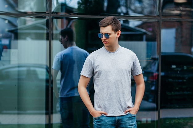 Een stijlvolle man in bril en grijs T-shirt. Straatfoto