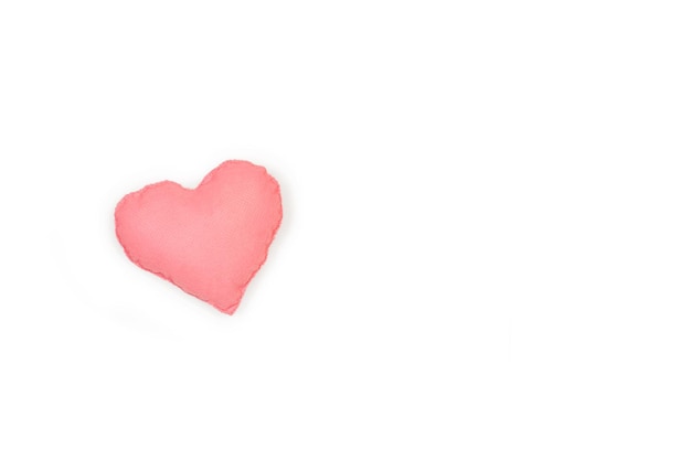 Een stoffen roze hart op een witte achtergrond met kopieerruimte