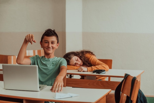 Een stoute jongen zit met zijn voeten op een bureau in de klas en gooit een vliegtuig Selectieve focus Foto van hoge kwaliteit