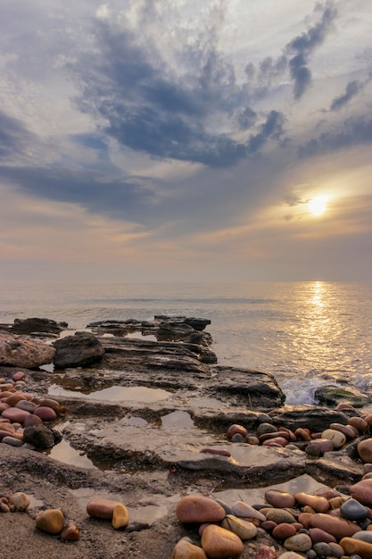 Een strand met een bewolkte lucht en een zonsondergang op de achtergrond