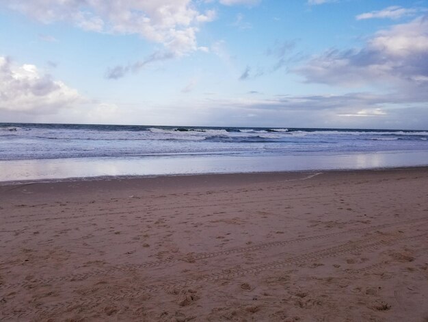 Een strand met een blauwe lucht en een paar wolken