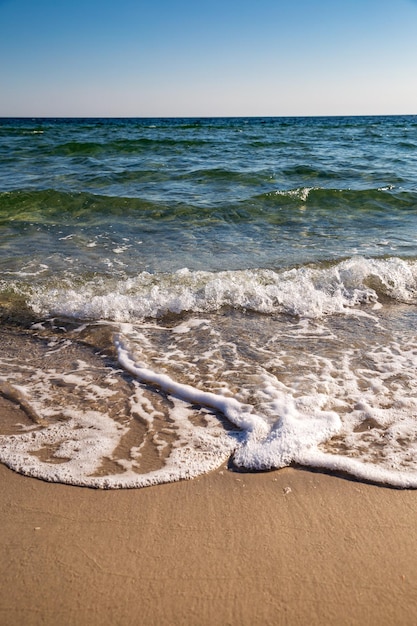 Een strand met golven en de zee op de achtergrond