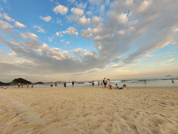 Een strand met mensen erop en een lucht met wolken op de achtergrond