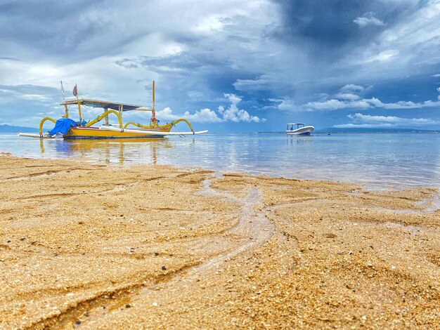 Een strandtafereel met een boot in het water en de lucht is bewolkt.