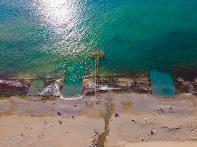 Een strandtafereel met een pier op de achtergrond