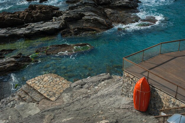 een strandterras gemaakt van planken op de kust met rotsen van de Middellandse Zee een rode reddingsboot