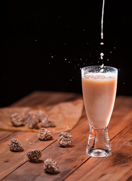 Een stroom melk wordt in een glas gegoten met een melkdrankje met een spatje druppels