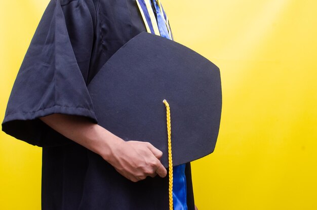 een student met afstudeerpet geïsoleerd op gele achtergrond