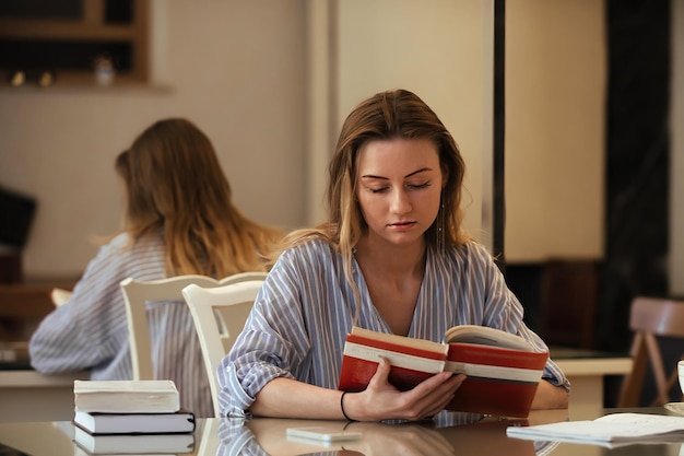 een student met lang blond haar in de eetkamer leest speciale educatieve literatuur