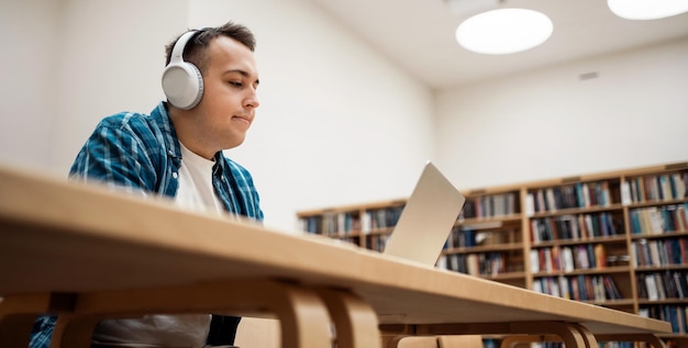 Een student studeert en luistert naar een audioboek met literatuur in de bibliotheek van de hogeschoolstudies