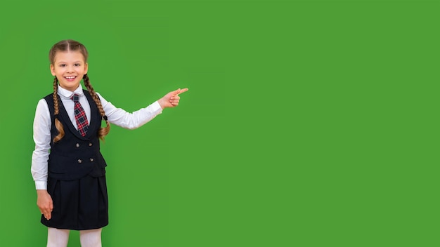 Een student toont een vrolijke student in een pak aan uw advertentie. het krijgen van een opleiding op de middelbare school. geïsoleerde groene achtergrond.