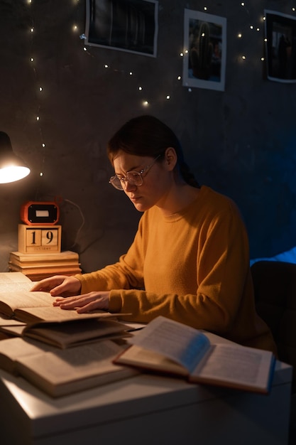 Een studentenvrouw die laat in de nacht boeken leest in de slaapzaal.