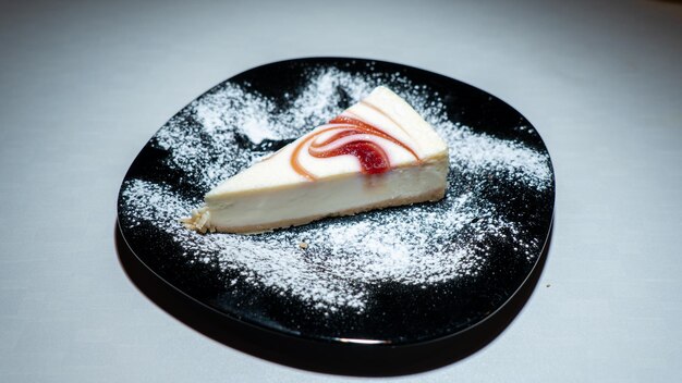 Een stuk cheesecake met een werveling van rood en wit erop.