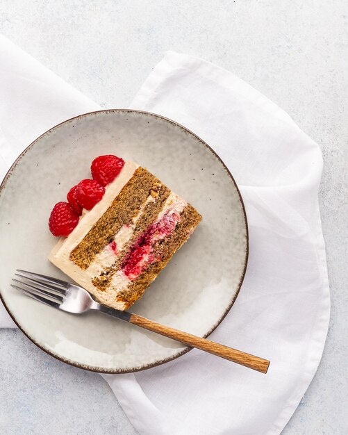 Een stuk frambozencake met frambozencake en verse frambozen op een witte achtergrond