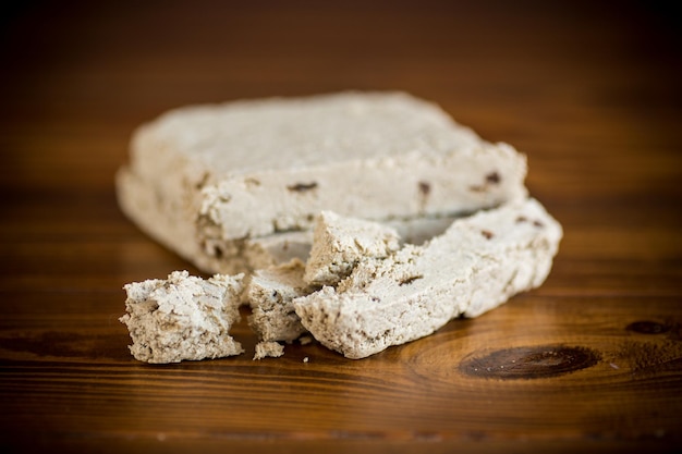 Een stuk gebroken zoete halva met zaden erin op een houten tafel