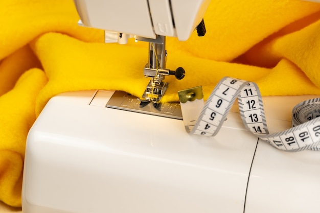 Een stuk gele stof op een naaimachine en een centimeter F.