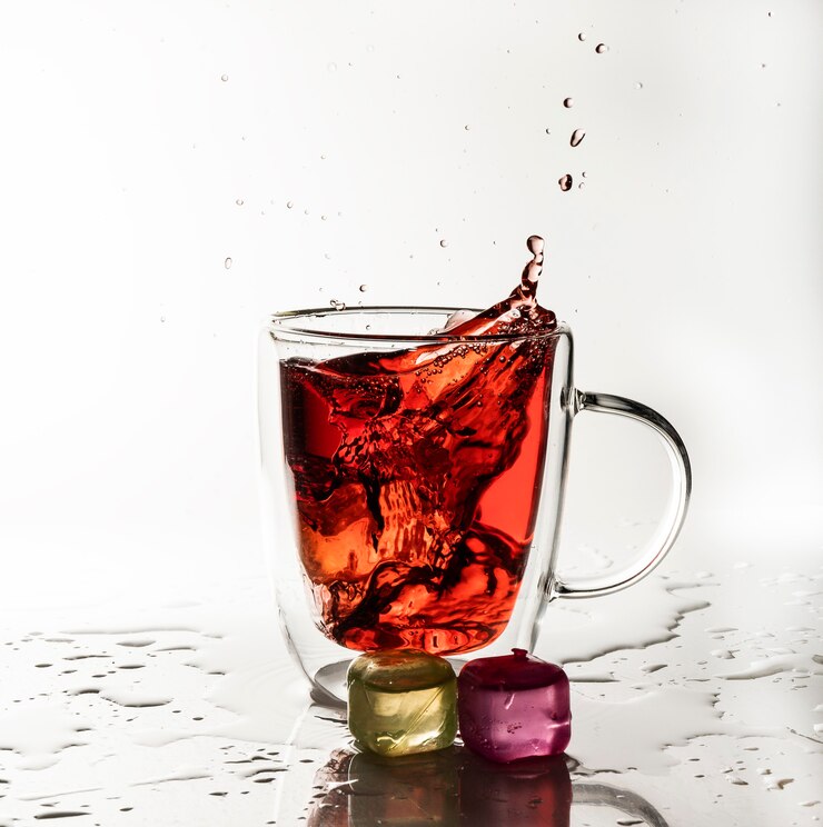 Een stuk ijs wordt in de rode drank gegooid