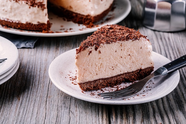 Een stuk koude chocolade cheesecake op een bord op houten rustieke achtergrond