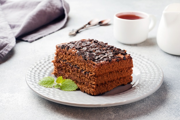 Een stuk van truffelcake met chocolade op een grijze concrete achtergrond.