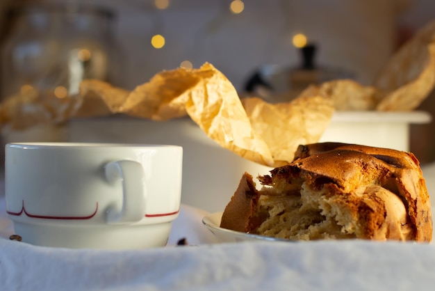 Een stuk versgebakken appeltaart en een witte mok koffie op een witte katoenen ondergrond