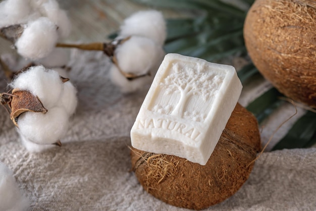 Een stuk witte zeep met het opschrift Natural en de afbeelding van een boomkokosnoot en katoen op tafel