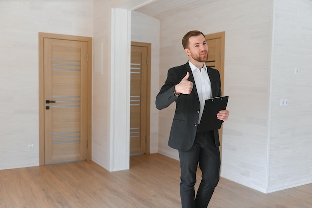 Een succesvolle makelaar staat in een nieuw modulair gebouw en biedt een nieuw huis aan