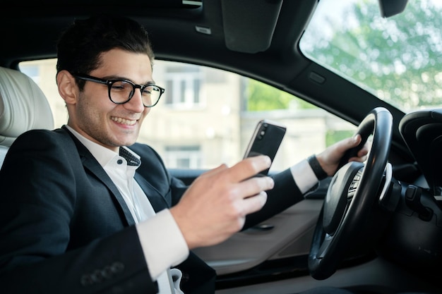 Een succesvolle zakenman is een chauffeur, een man die een bericht aan de telefoon schrijft met behulp van een applicatie