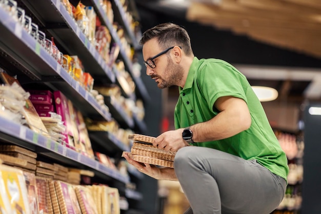 Een supermarktmedewerker hurkt naast een schap en toont boodschappen op de markt