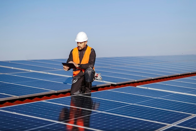 Een supervisor knielt en controleert de juistheid van zonnepanelen op het dak